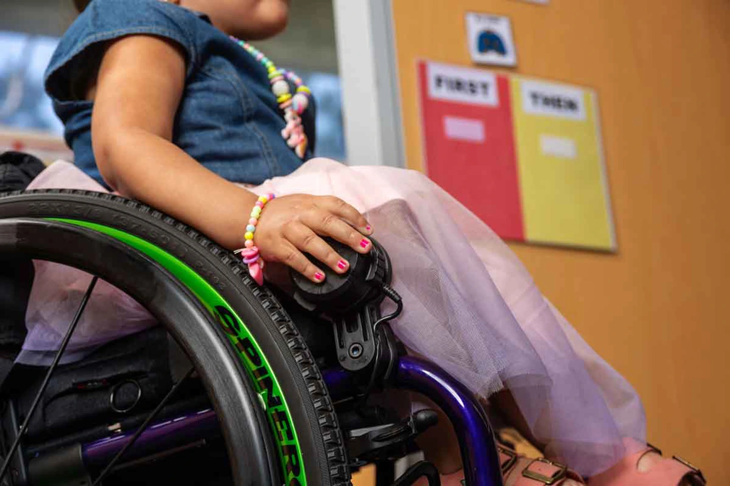 Image of woman using the Permobil Speed Control Dial - Wired speed control for Permobil SmartDrive power wheelchairs. Simple rotary dial allows intuitive start, stop, and speed adjustment.