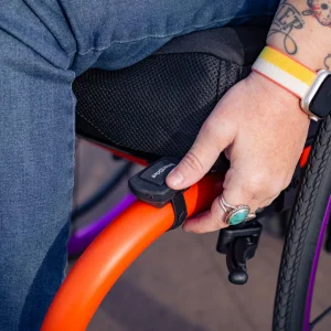 Image of a woman using the SmartDrive MX2+ Switch Control - Compact, wireless switch control for power wheelchairs, enabling users to activate various functions with a simple press or touch.