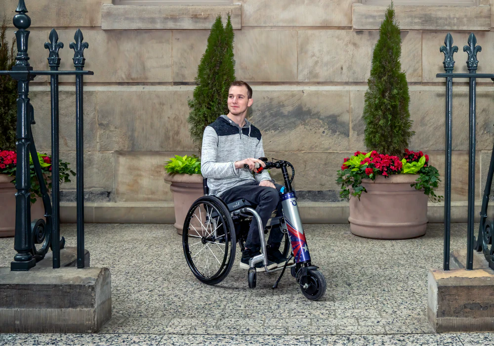 Image of a young man using his Cheelcare Companion - Lightweight, portable power assist device for manual wheelchairs, offering increased mobility and independence.