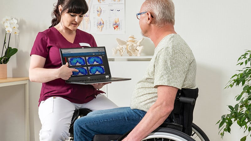 Image of a woman teaching a man about the Star Sentinel - Innovative standing wheelchair that allows users to transition from seated to standing positions, promoting improved circulation, pressure relief, and social interaction.