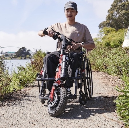 Front view of an adventurous man driving his Rio Firefly 2.5 - Electric Power Assist for Manual Wheelchairs through a scenic trail.