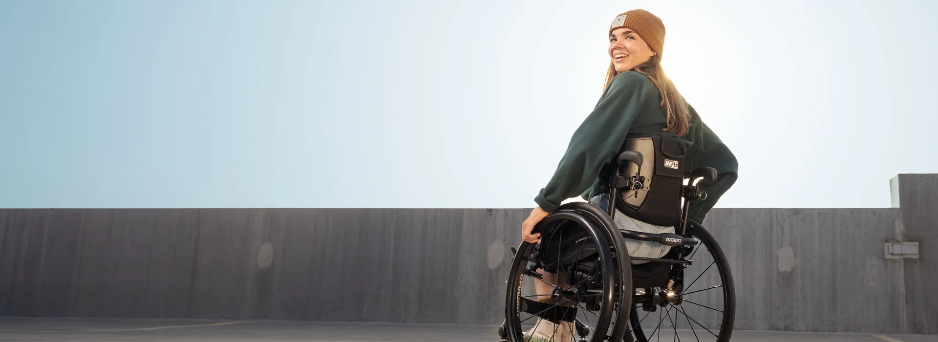 Image of a woman happily using the Jay J3 Carbon Fiber Backrest - Lightweight, adjustable wheelchair backrest with a carbon fiber shell for optimal support, posture, and comfort.