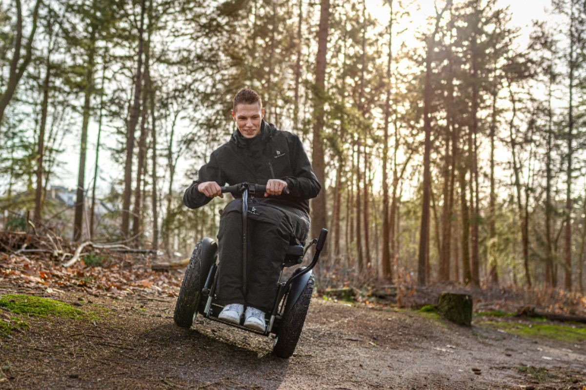 Image of a youthful man enjoying his Kinetic Balance Raindek Raider - Transparent wheelchair cover protecting user from rain and wind.