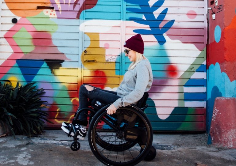 Side view of a woman on a SMOOV one Wheelchair - Stylish and ultra-lightweight folding wheelchair with single-sided frame for easy side transfers.