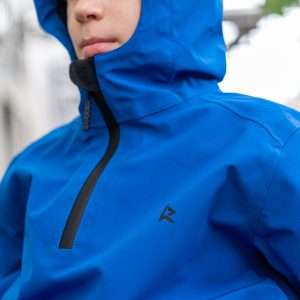 Close up image of the blue Kinetic Balance Raincape Junior - Waterproof, breathable raincoat for children in wheelchairs, featuring adjustable hood and arm protectors.