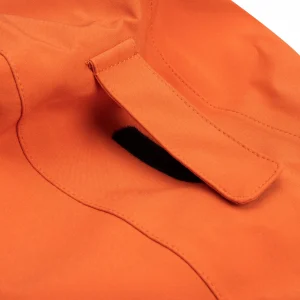 Close up image of the orange Kinetic Balance Raincape Junior - Waterproof, breathable raincoat for children in wheelchairs, featuring adjustable hood and arm protectors.