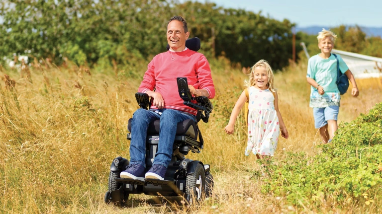 Image of a happy man and his children using the Permobil VoltPro Charger and Battery - High-performance rechargeable battery and charger for Permobil power wheelchairs, providing extended range and efficient charging.