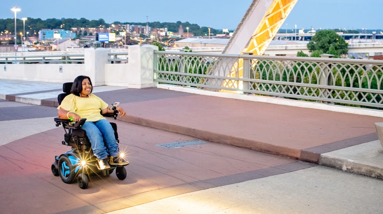 Image of a happy woman using the Permobil VoltPro Charger and Battery - High-performance rechargeable battery and charger for Permobil power wheelchairs, providing extended range and efficient charging.